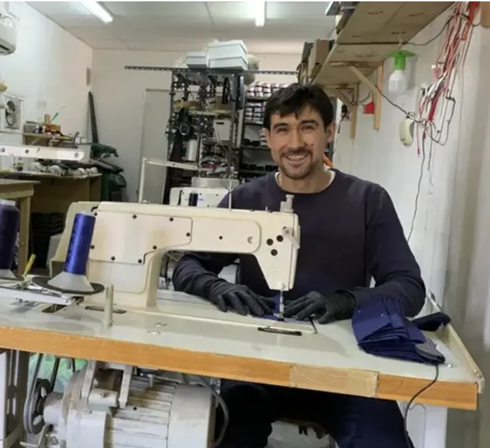 Darío Jara sentado frente a una máquina de coser en su taller